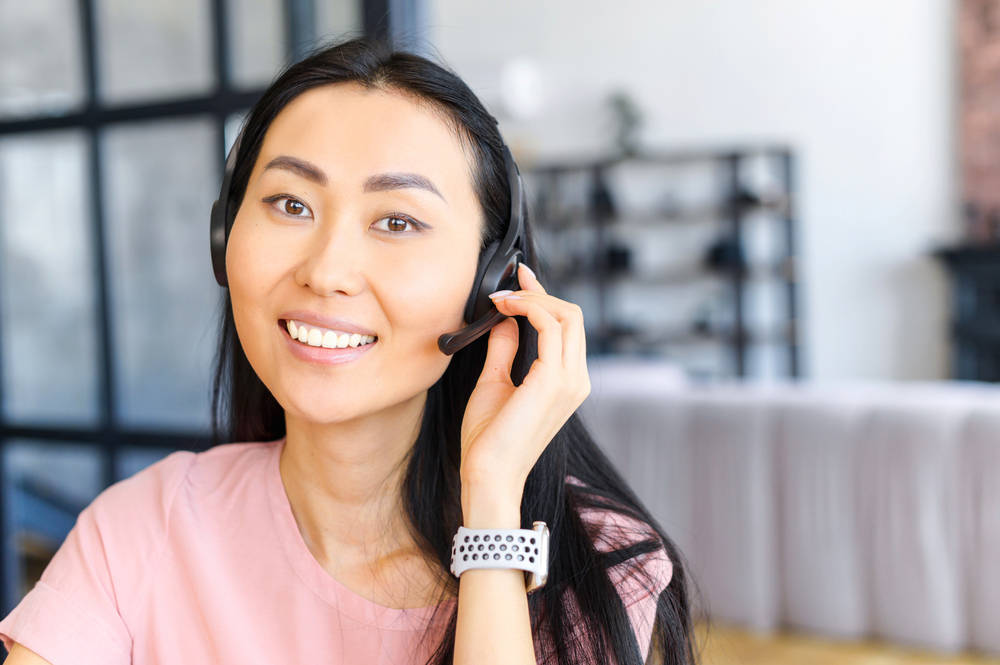Confident,Asian,Female,Consultant,With,Headset,,Looking,At,Camera,,Talking